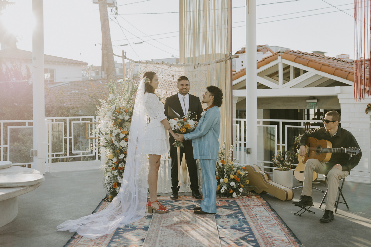 Couple holding hands in front of wedding officiant.