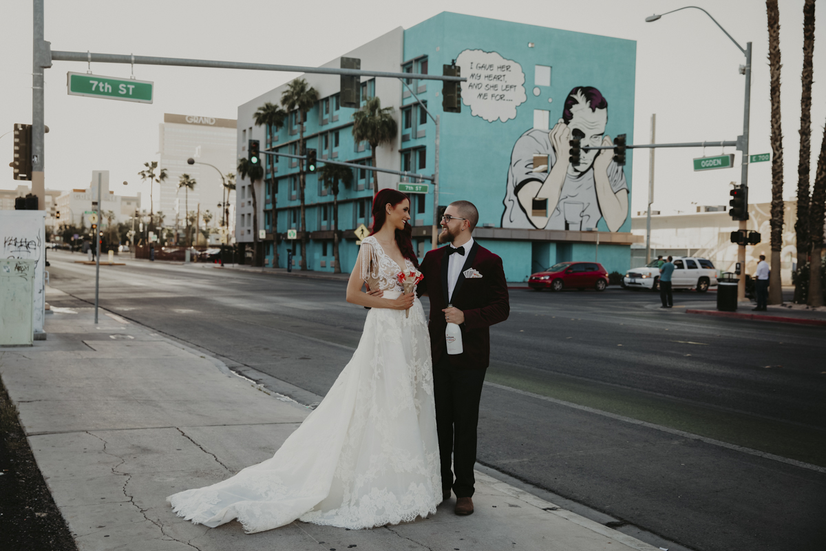 Bride and groom standing in front of building with mural.