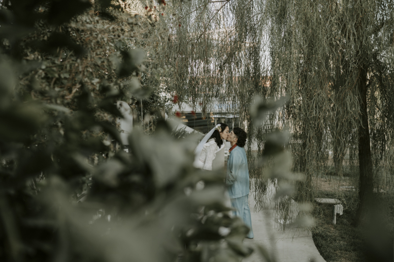 View of newlywed couple through trees.