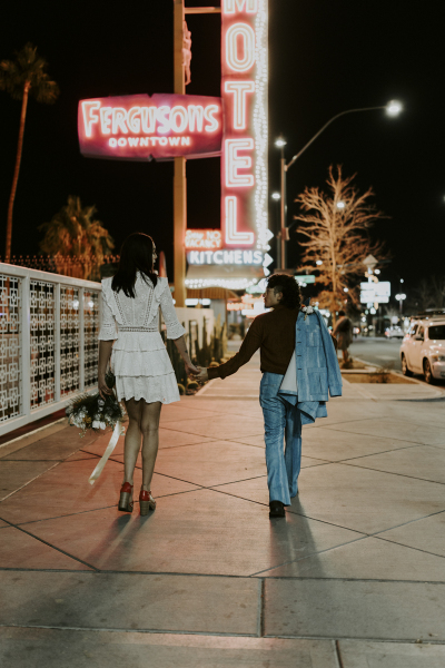 Bride and groom holding hands walking on Las Vegas sidewalk.