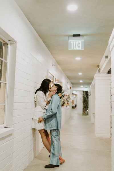 Newlywed couple kissing in hallway.