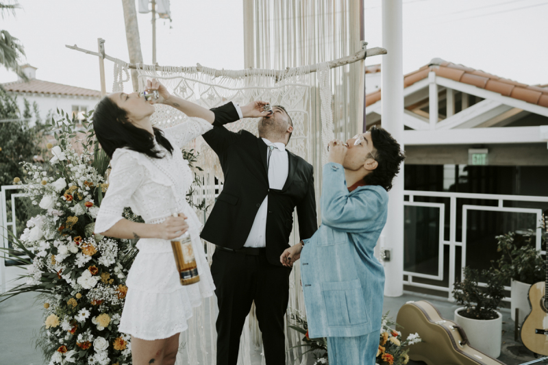 Bride, groom and officiant taking a shot.