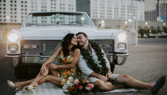 Couple sitting in front of car sticking their tongues out.
