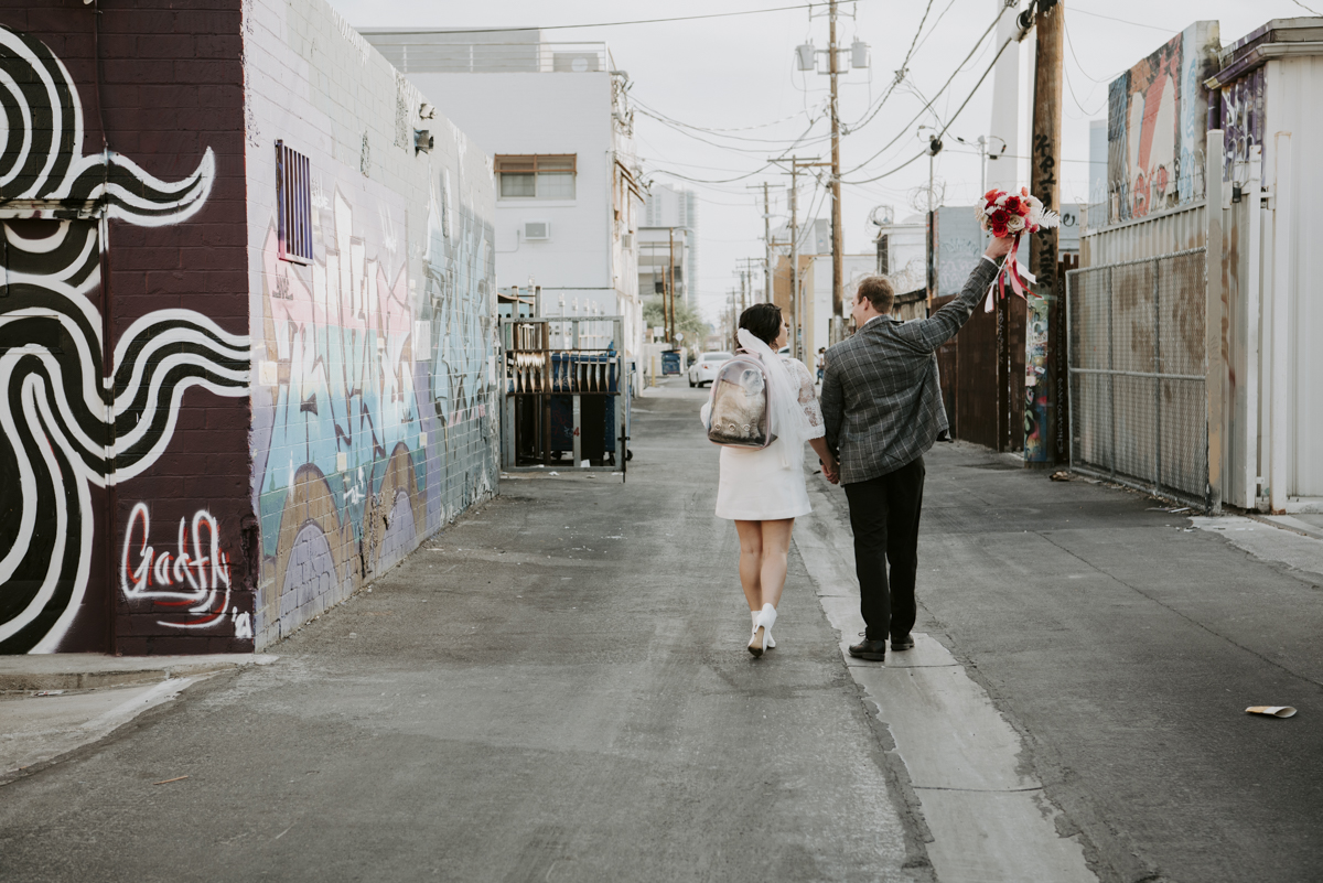 Newlywed couple walking in downtown LV alley.