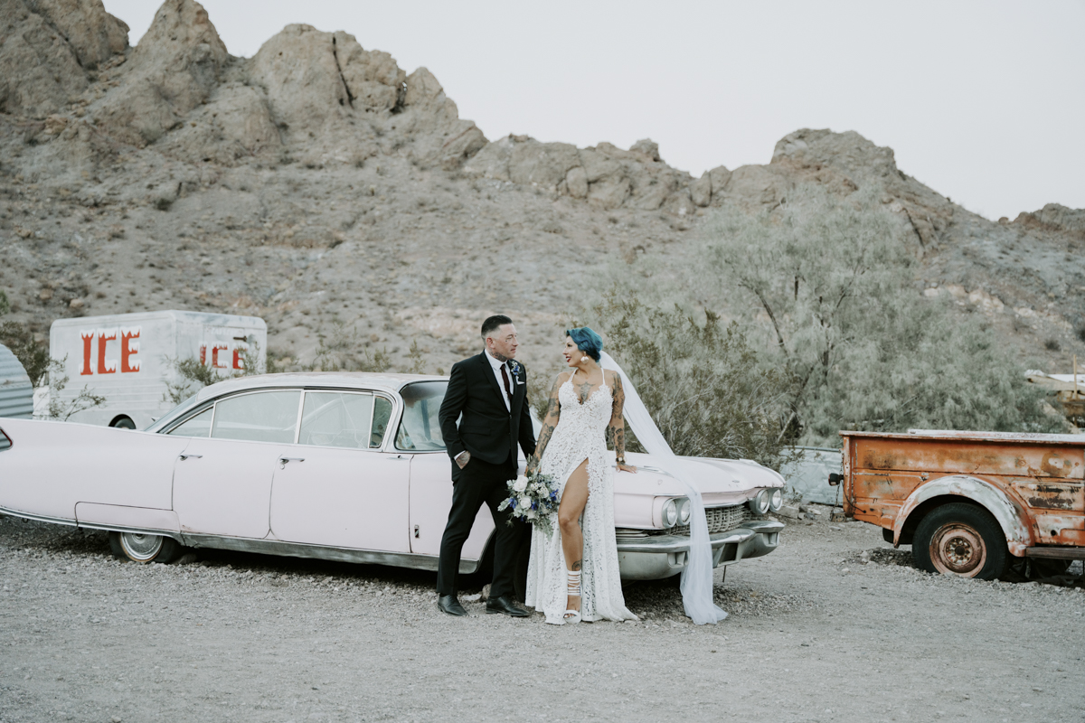 Bride and groom standing next to classic car at Eldorado Canyon.