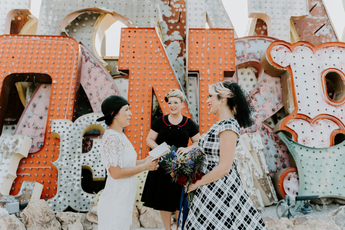 two brides with an officiant at the neon museum