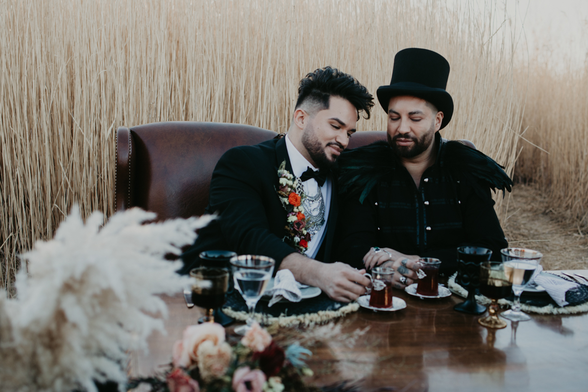 Two gothic grooms in a field of wheatgrass.