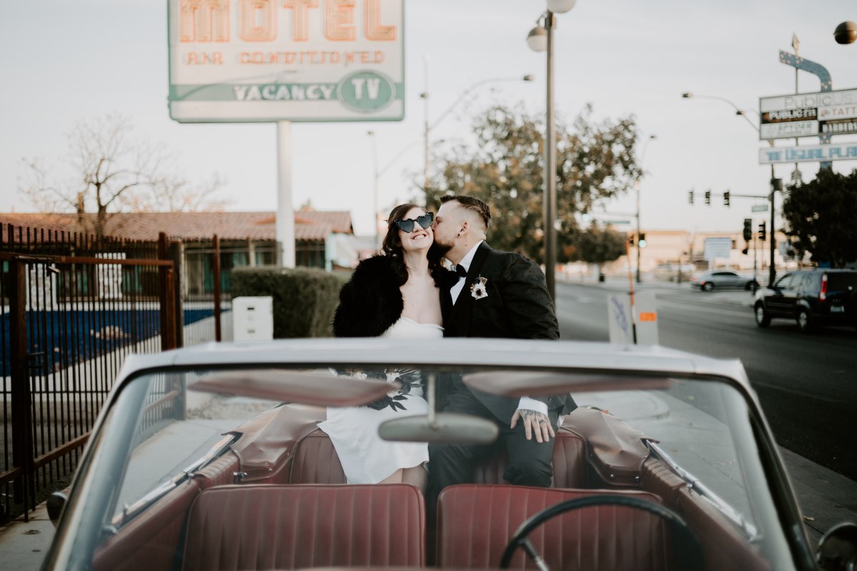 unique vegas elopement 1 wedding couple sitting in a classic convertible car in front of a Las Vegas hotel sign
