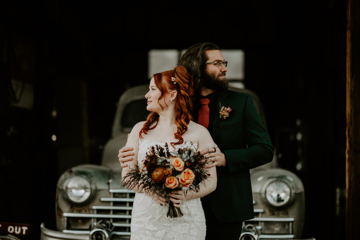wedding video trends feature bride and groom standing together in front of a vintage truck